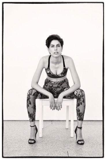 Black and white photograph model seated in studio.