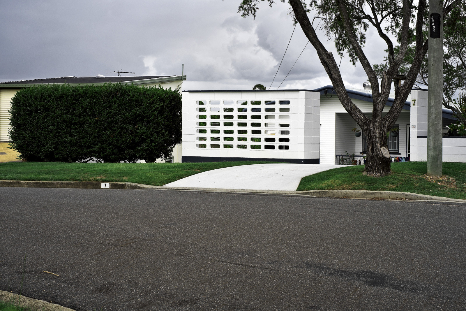 1950's 60's weatherboard home below the roadline with breeze block privacy wall, Canon Hill, Brisbane. Architectural photography by Kent Johnson.