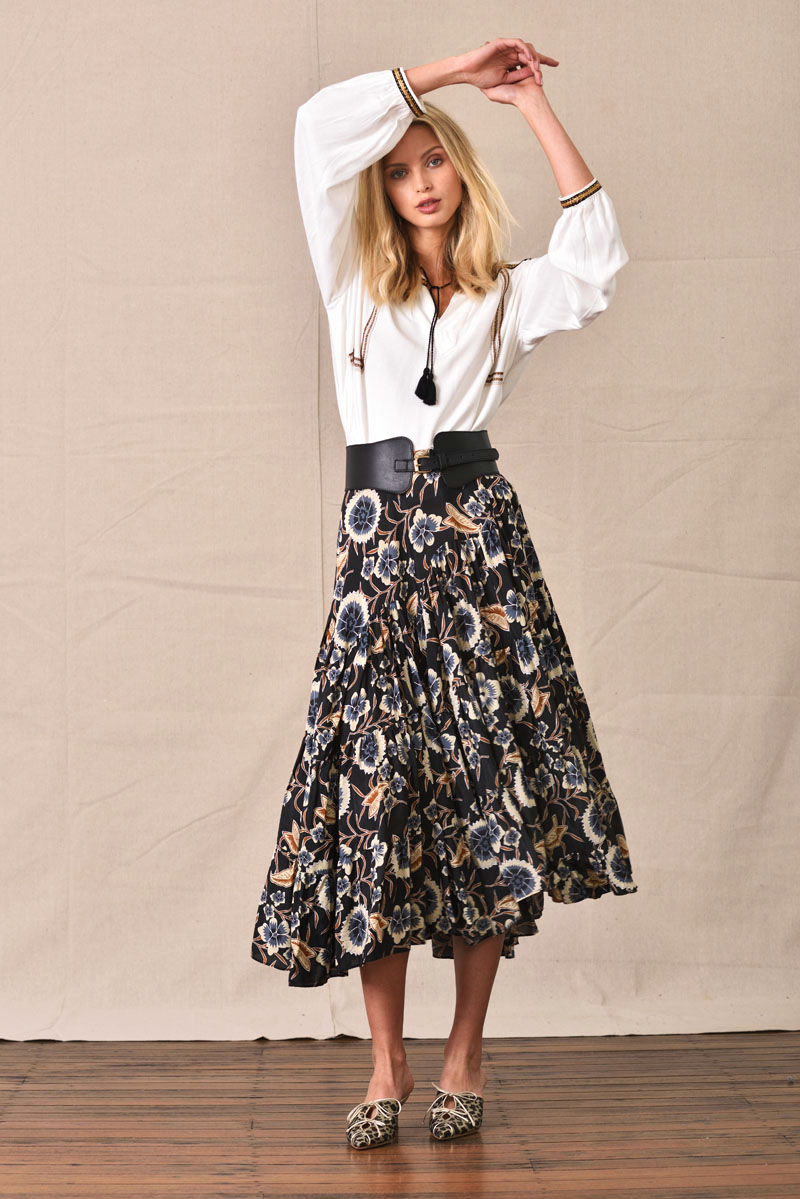 White boho blouse with tassels, matched with long flowing floral-on-black skirt - eCommerce Studio Fashion Photography by Kent Johnson. Fashion marketing campaign, model on white background.