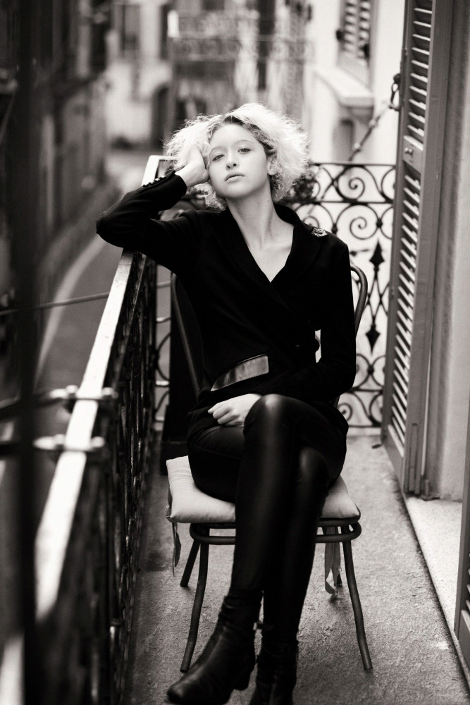 Young female model sitting on a Juliet balcony in central Milan.