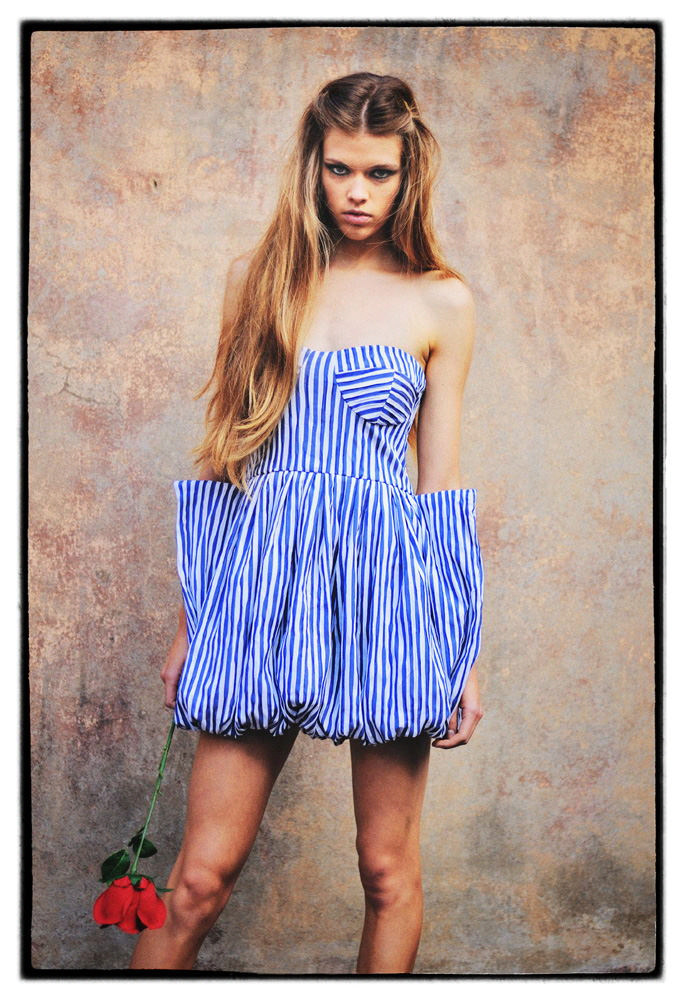 Model in a blue and white striped dress holding a rose. Lulu Label.