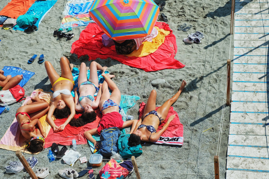 Overhead view of young women in bikinis lying on a beach on the Italian Riviera.