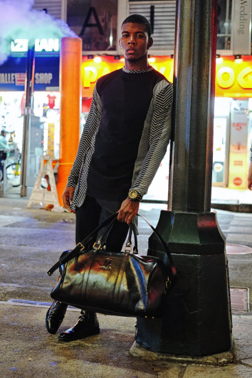 Male model leaning on a post box wearing chevron coat.