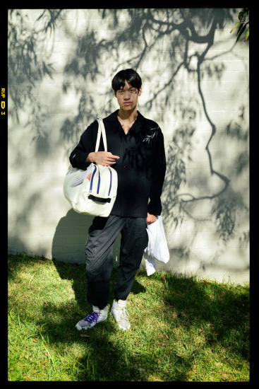 Street style, a fashionable young Asian man on a shadowy suburban street in Sydney, Australia.