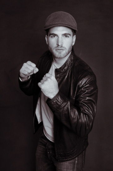 Shadow boxer, male model in cap, white tee and leather jacket.