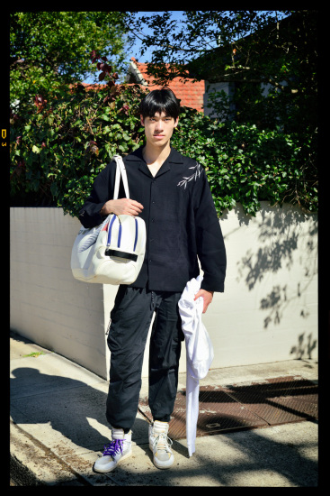Street style, a fashionable young Asian man on a suburban street corner.