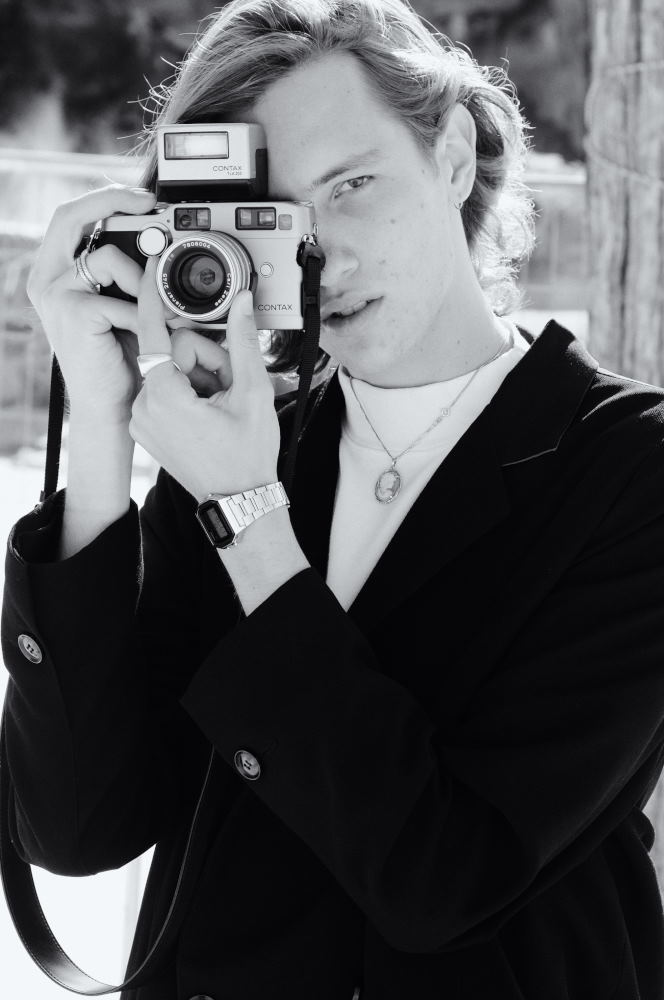 Male model with vintage camera, portfolio shoot at a Sydney beach location.