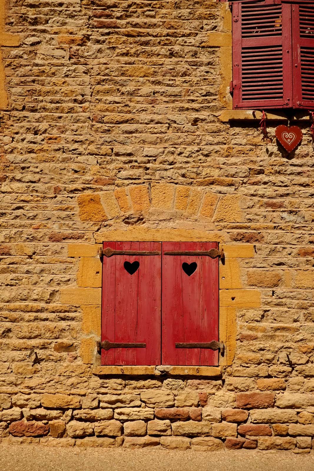 Red shutters and carved hearts feature in the golden stone house walls of Oint. Photography by Kent Johnson.