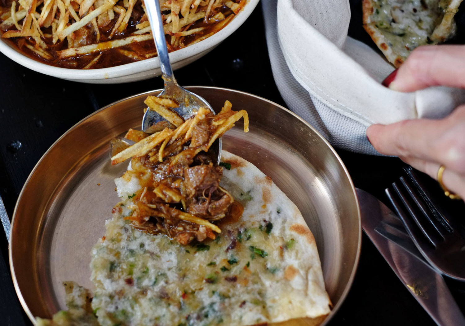 Plating a serve of Salli Botti with Cheese Chilli Coriander Naan at Masala Theory. Chef ’s special goat curry, black cardamom, cinnamon, onion and tomato gravy, match-stick potatoes. Photographed by Kent Johnson for Street Fashion Sydney.