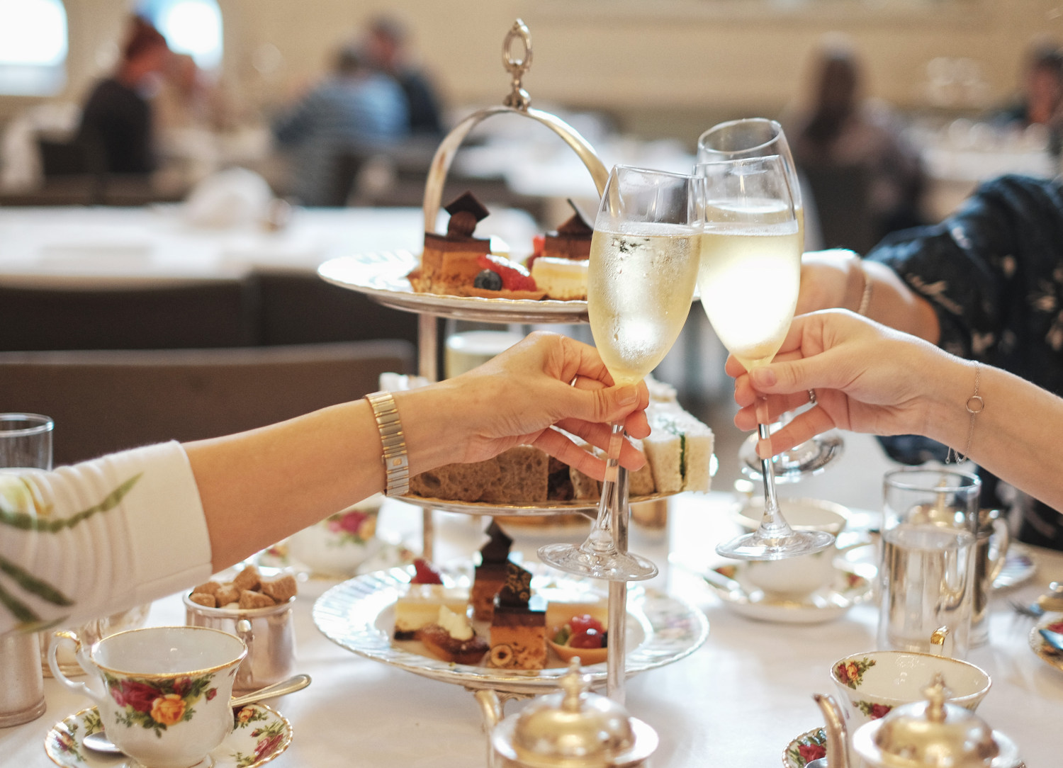 Champagne flutes raised in a salute of greeting, Queen Victoria Tea Room - Sydney, Australia. Photography by Kent Johnson for White Caviar Life.