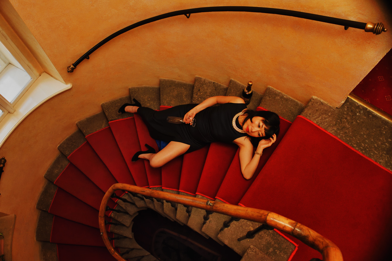 Woman reclining on a spiral staircase in a 15C hotel Alchymist Nosticova in Prague. Interior architecture photography by Kent Johnson.