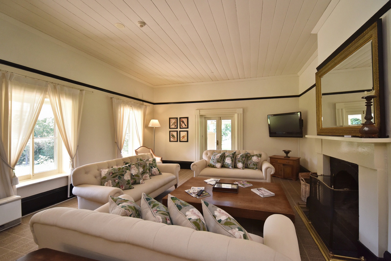 The lounge room with open fireplace couches and TV, one of many common area rooms at the historic Fitzroy Inn, Mittagong in the Southern Highlands. Hotel interior photography by Kent Johnson.