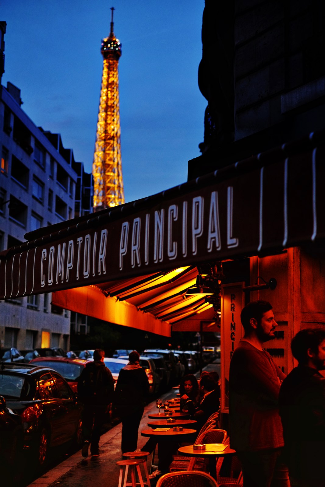 A street view of the Eiffel Tower and classic french bistro at night. Lifestyle photography by Kent Johnson.