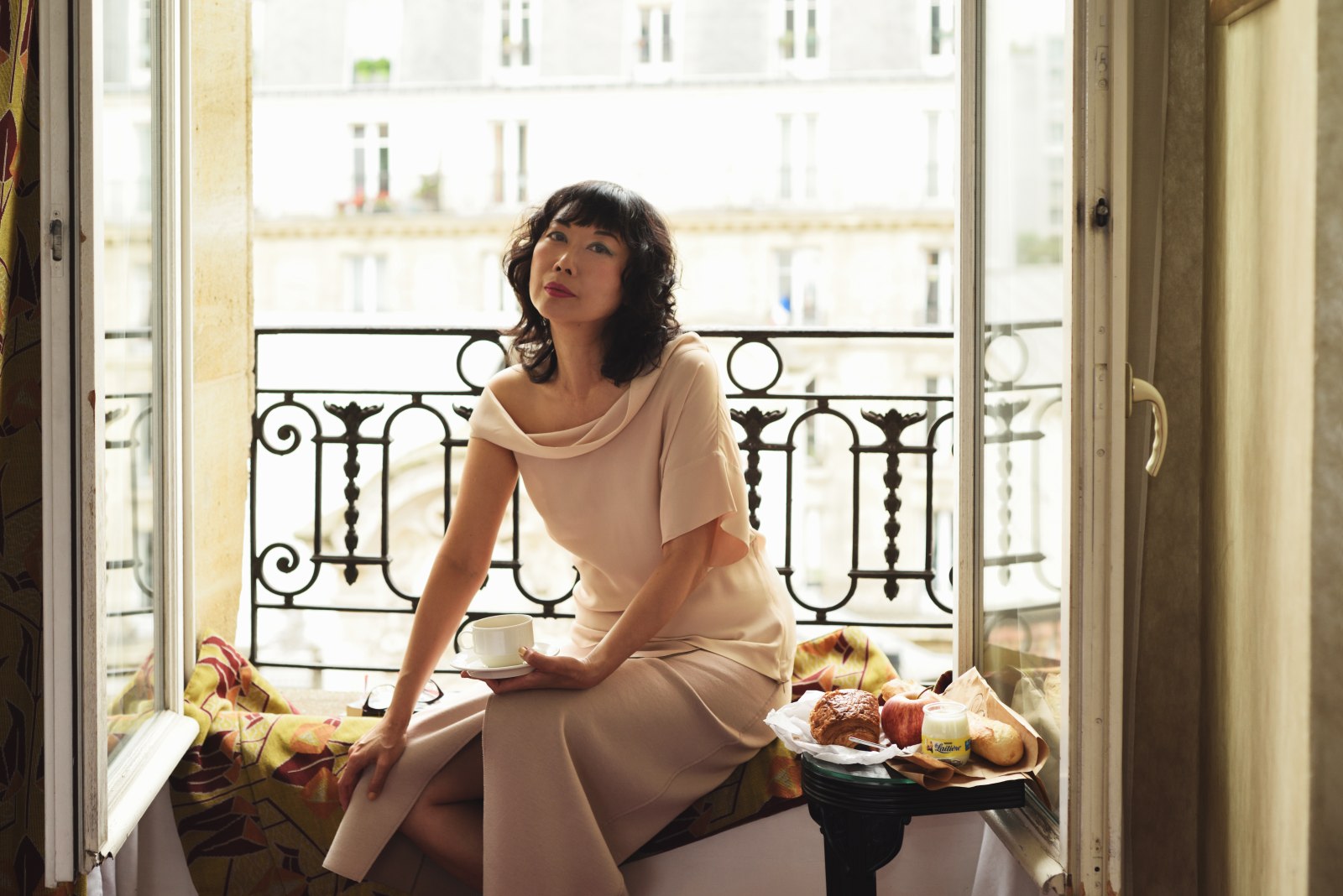 Window portrait in a Paris hotel of Vivienne with coffee and a breakfast tray. Food and travel lifestyle photography by Kent Johnson.