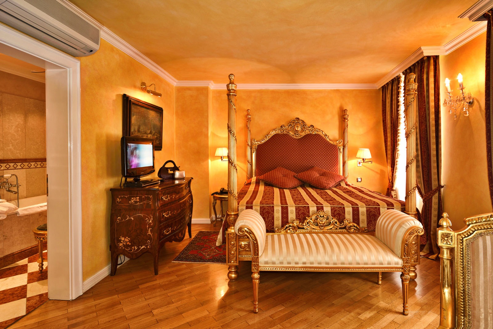 Gilt gold furniture and red and gold brocade fabrics decorate a luxury baroque era hotel room in Prague