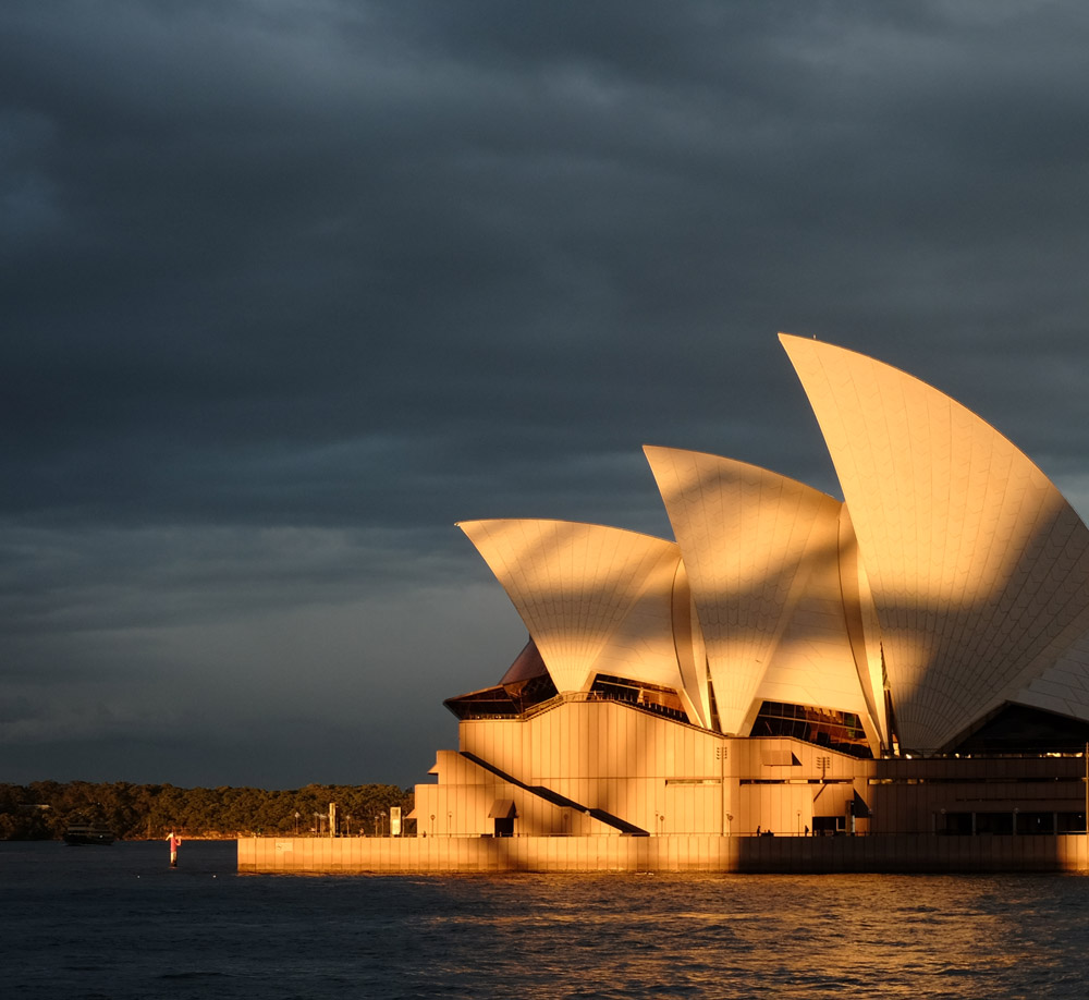 Sydney Opera House and Circula Quay at sunset with the shadow of the Harbour Bridge. Panorama and Travel photography by Kent Johnson.