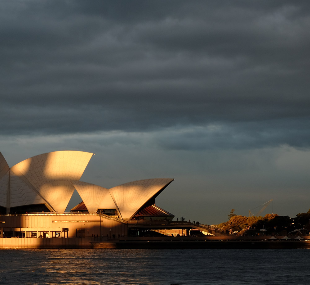 Sydney Opera House and Circula Quay at sunset with the shadow of the Harbour Bridge. Panorama and Travel photography by Kent Johnson.