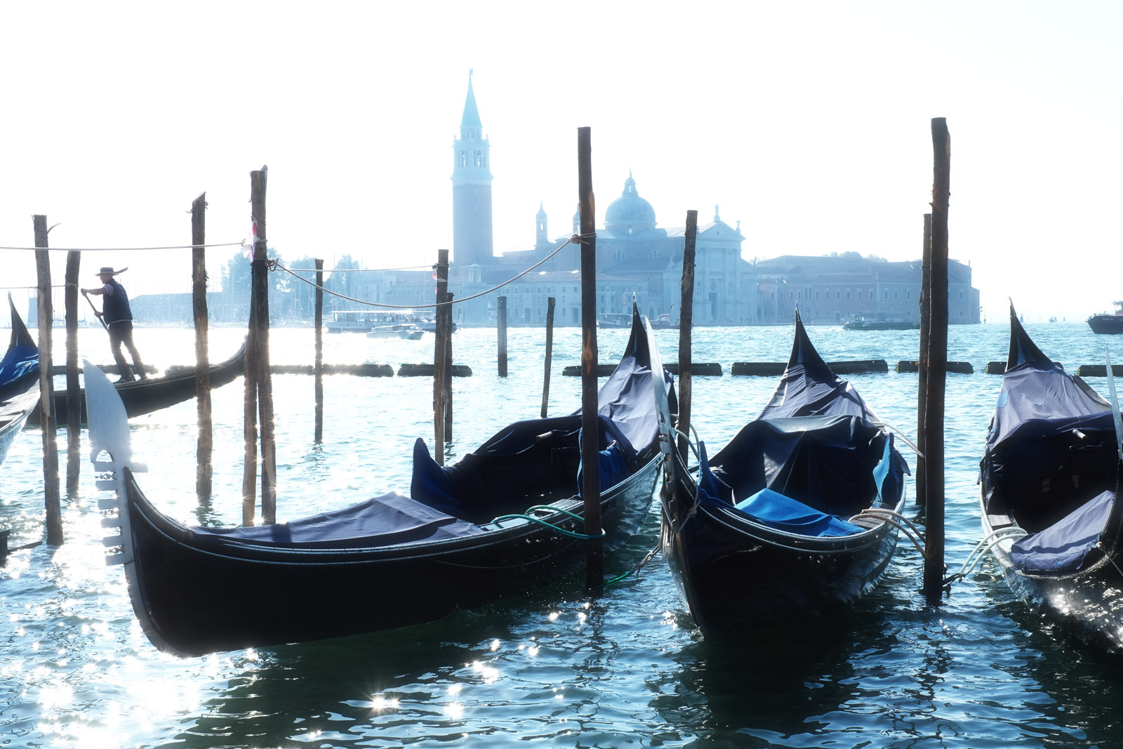 Gondolas moored by San Marco in a blue dawn light, Church of San Giorgio Maggiore in the background. Travel lifestyle and architecture photography by Kent Johnson.