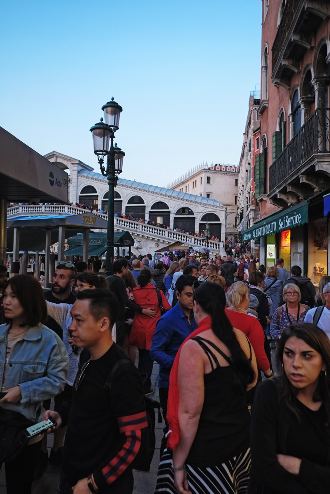 Travellers and toursists swarm the Rialto bridge and quay side. Street style travel photography by Kent Johnson.