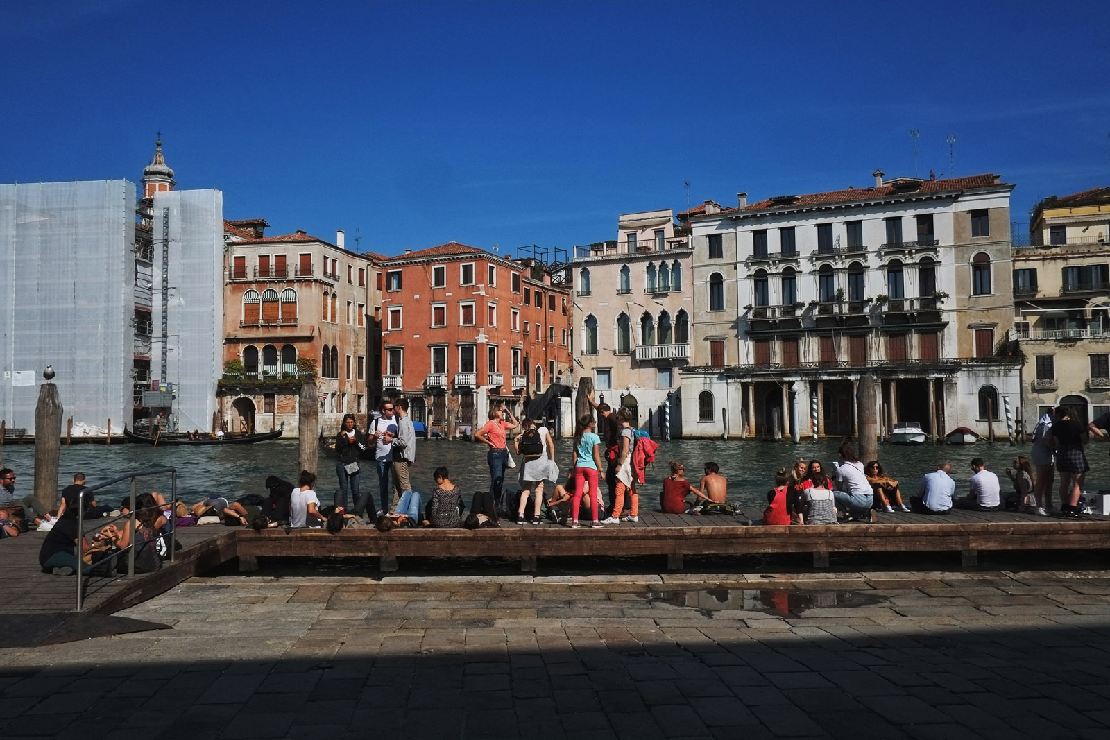 Tourists sitting on pontoon, Grand Canal near Rialto